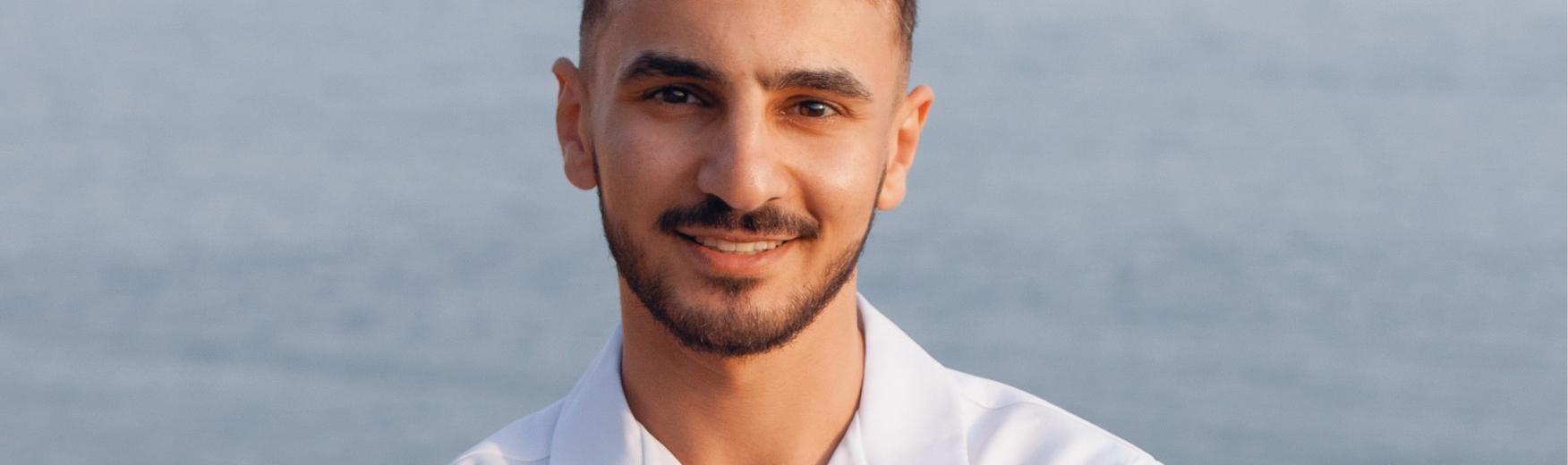 Homme (Aymen) en train de sourire à la caméra à côté de la plage, représentant l'entrepreuneuriat jeune